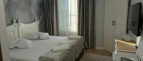 A bedroom with a bed, a TV, a wardrobe, and a desk.