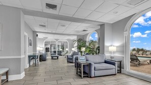 A spacious lobby with a modern design, featuring a long reception desk, comfortable seating areas, and large windows offering a view of the outdoors. - Bluewater Resort 1BR Condo Steps From Beach (Myrtle Beach)