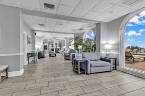 Eine geräumige Lobby mit modernem Design, ausgestattet mit einer langen Rezeption, gemütlichen Sitzbereichen und großen Fenstern mit Blick ins Freie.