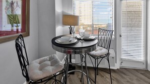 A dining area with a round table, two chairs, a lamp, and a framed picture on the wall. - Bluewater Resort 1BR Condo Steps From Beach (Myrtle Beach)