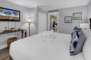 A hotel room with a large bed, a flat-screen TV, a desk with a lamp, and a kitchenette in the background. - Bluewater Resort 1BR Condo Steps From Beach (Myrtle Beach)