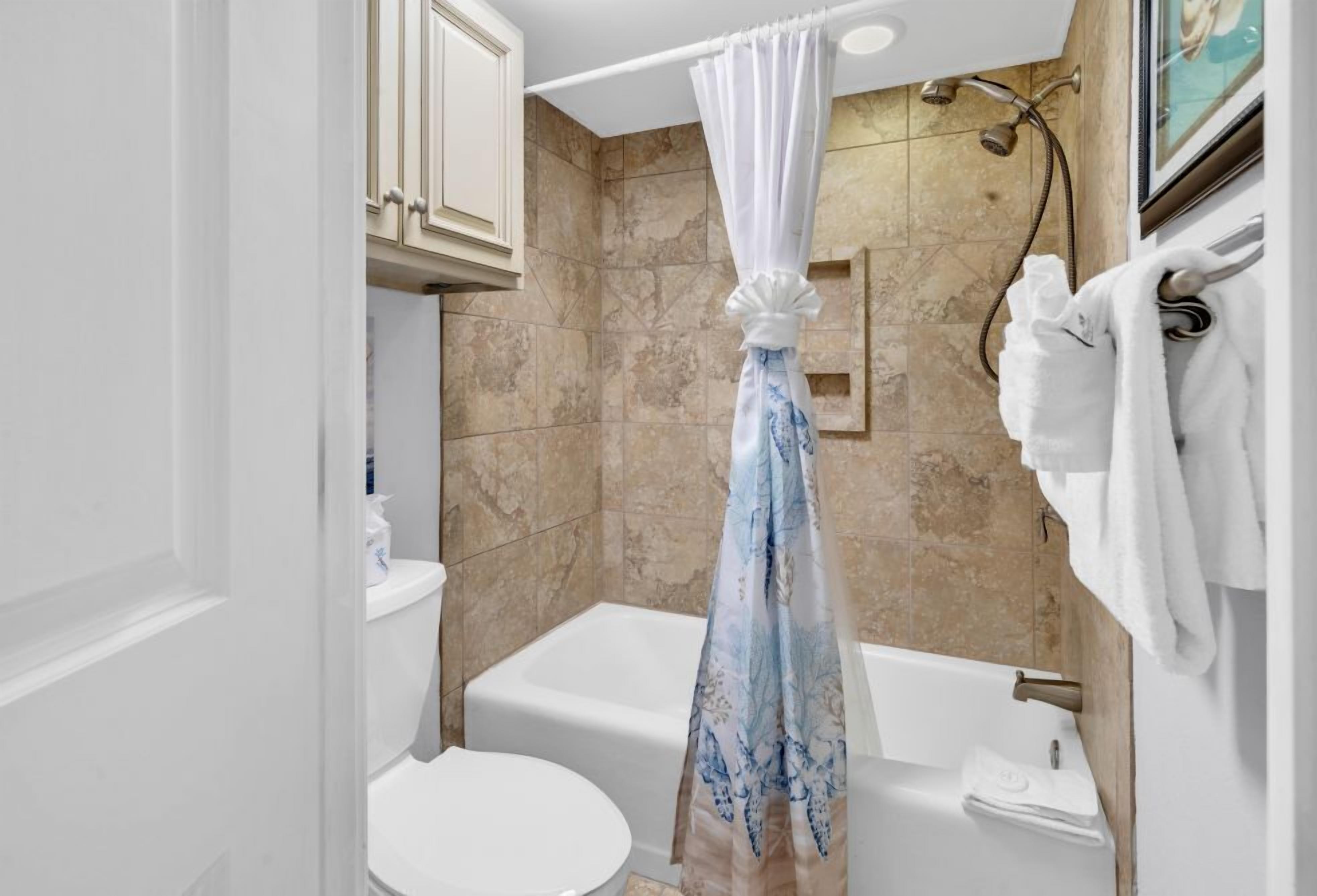 Een badkamer met een bad, toilet en douche.
