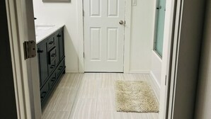 Un pasillo con una puerta blanca, un cuadro en la pared, un armario oscuro y una alfombra clara.