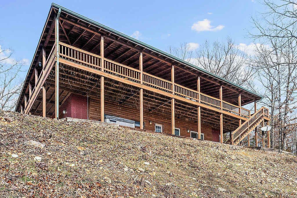 Un grand bâtiment en bois doté d’un balcon, d’un escalier et d’une porte rouge.