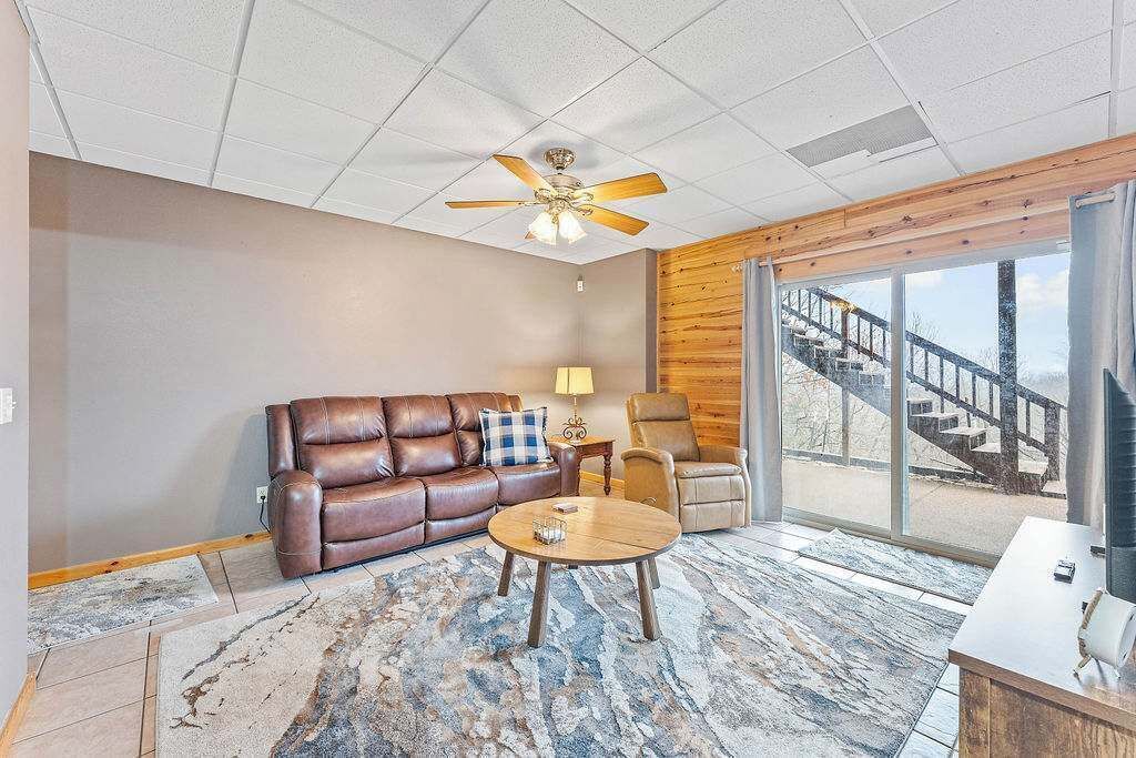 A modern living room with a leather sofa, a round coffee table, and a ceiling fan.