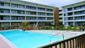 Un hotel con piscina, varios balcones y una pared de piedra.