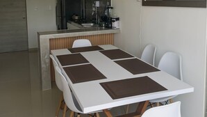 Una cocina moderna con armarios blancos, horno empotrado y cafetera.