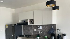Una cocina moderna con armarios blancos, un refrigerador negro, una estufa a gas, un lavamanos y una cafetera.