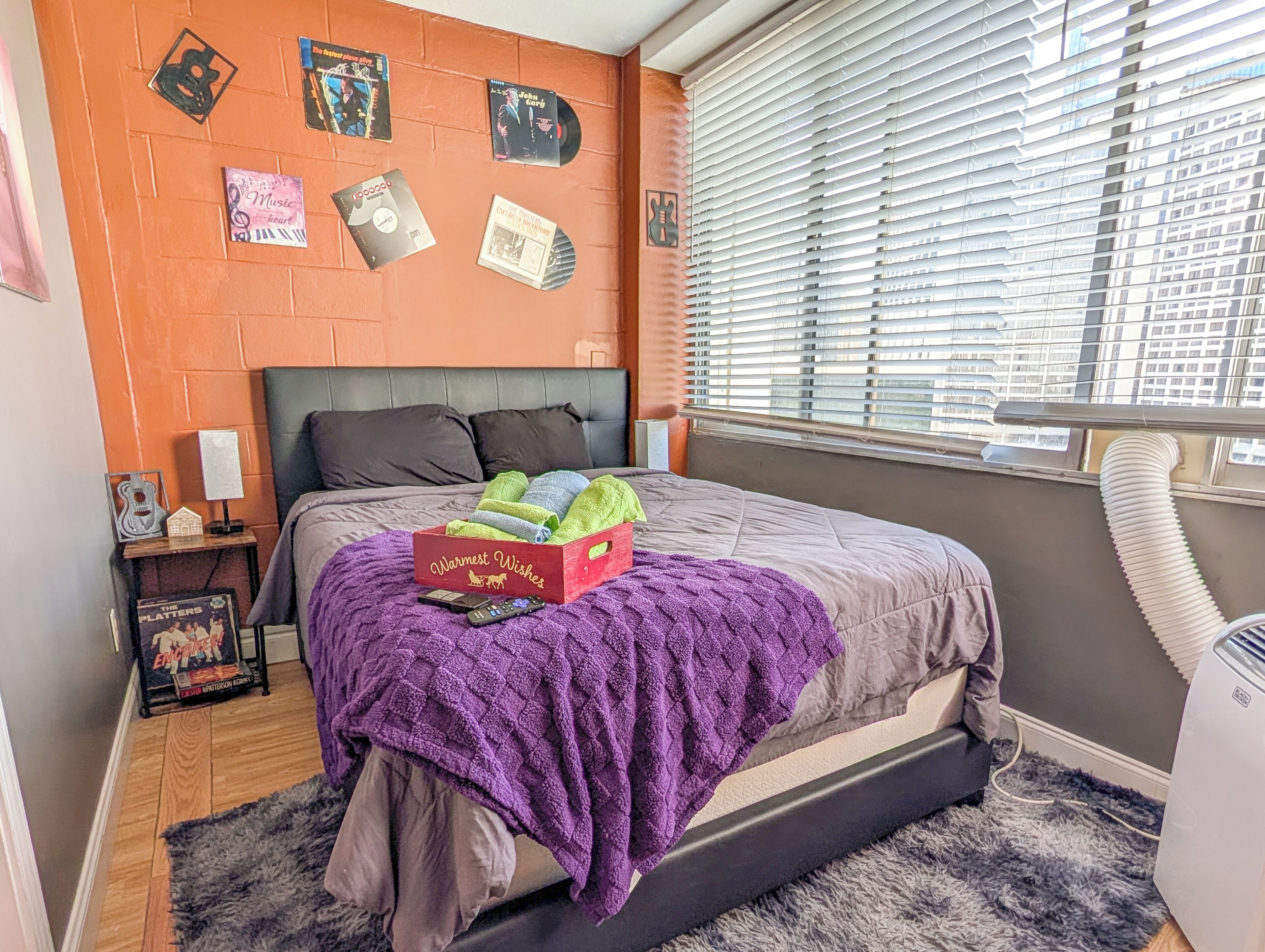 Un dormitorio con cama, ventana con persianas, radiador y decoración en la pared.