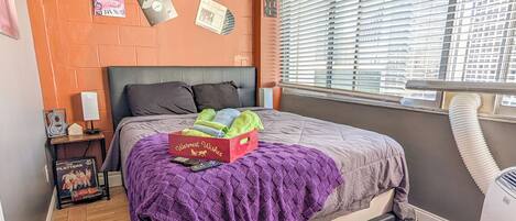 Un dormitorio con cama, ventana con persianas, radiador y decoración en la pared.