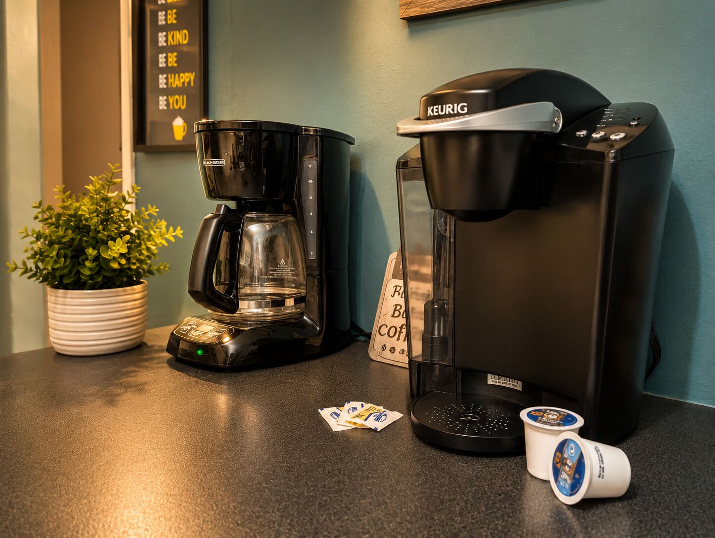 Une machine à café, une plante en pot et des capsules de café sur un plan de travail.