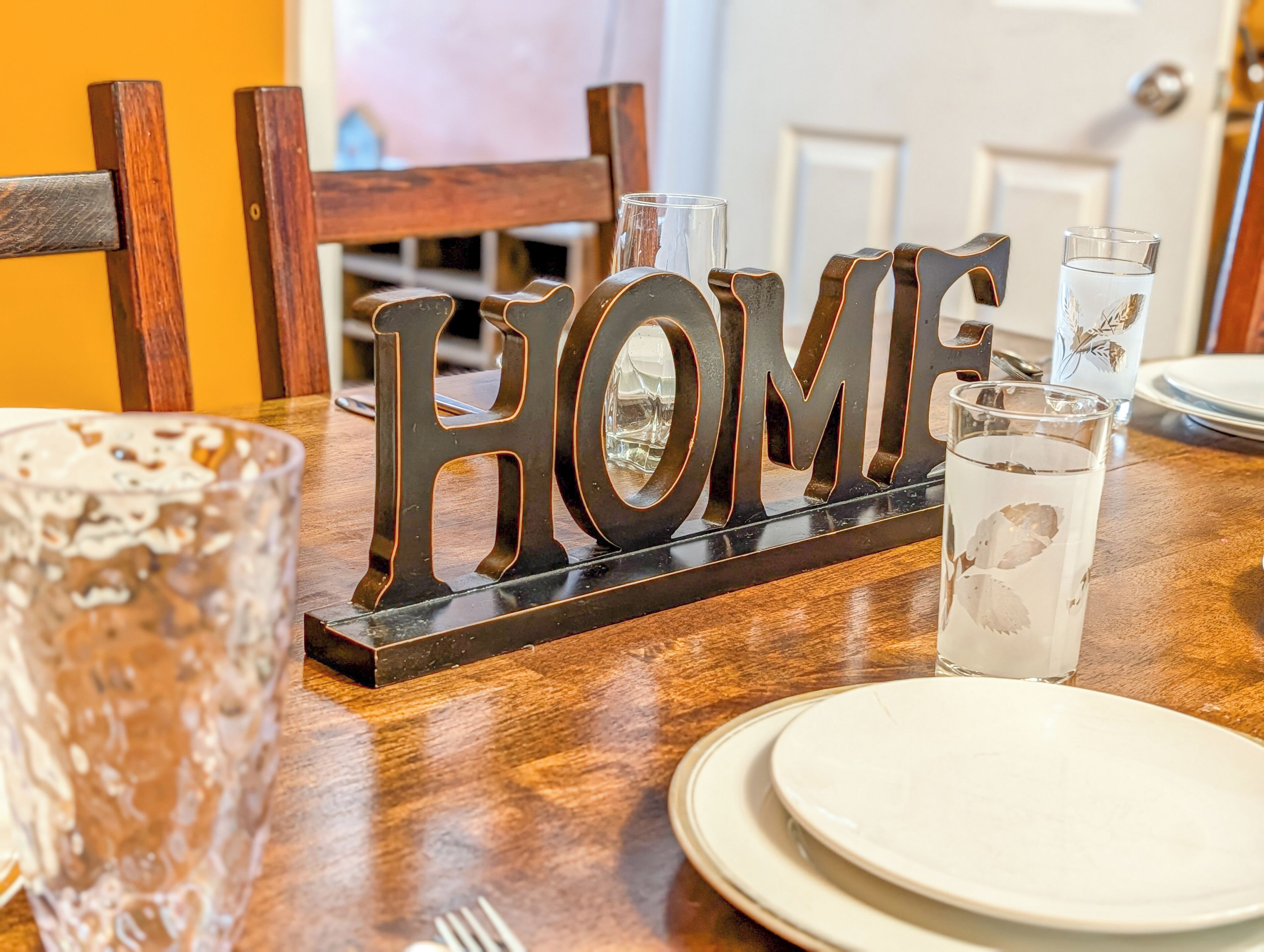 A dining table with a 'HOME' sign, glasses, and plates.
