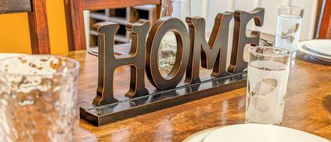 A dining table with a 'HOME' sign, glasses, and plates.