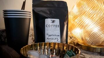A coffee bag, disposable cups, and a metal bowl with utensils.