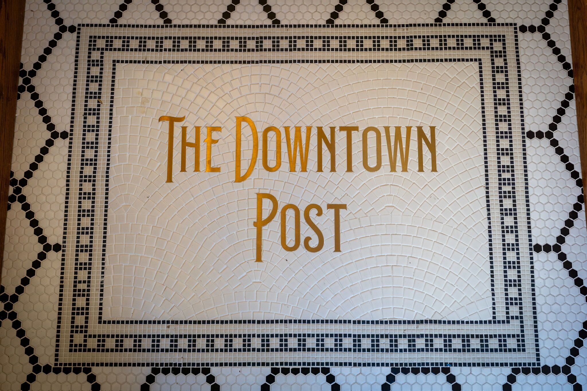 A mosaic sign with "The Downtown Post" written in gold letters.