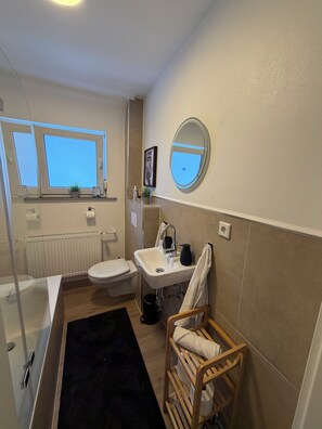 A bathroom with a window, a sink, a toilet, a mirror, and a towel rack. - Modern 75-square-meter apartment with a balcony - Quiet location near Winterberg (Winterberg)