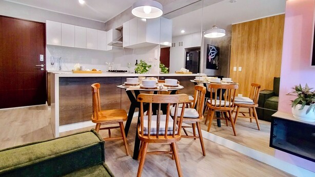 Une cuisine moderne avec des meubles blancs, un îlot central et des chaises en bois.