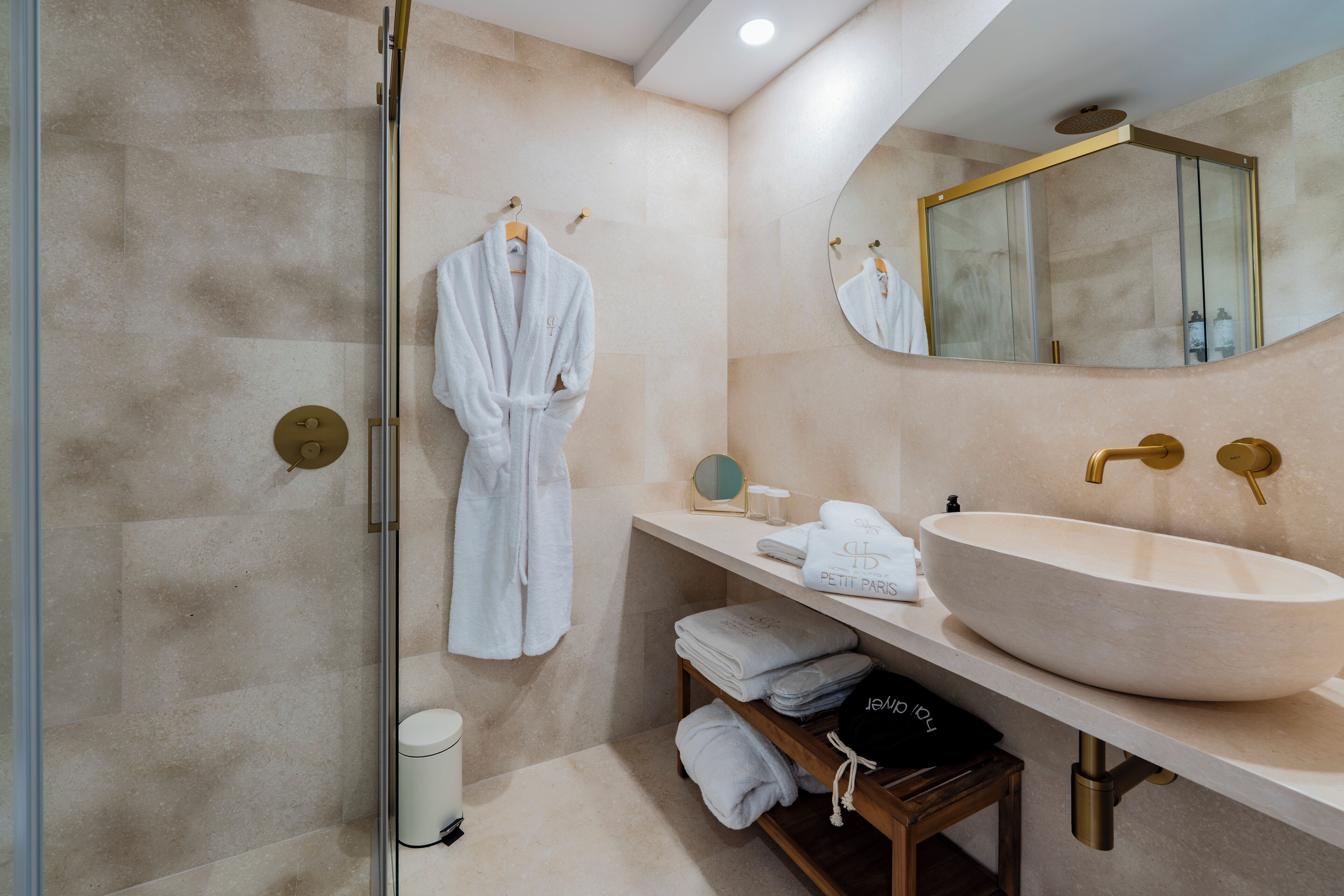 A modern bathroom with a large beige sink, a mirror, and a robe hanging on a rack.