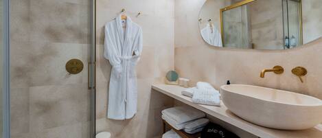 A modern bathroom with a large beige sink, a mirror, and a robe hanging on a rack.