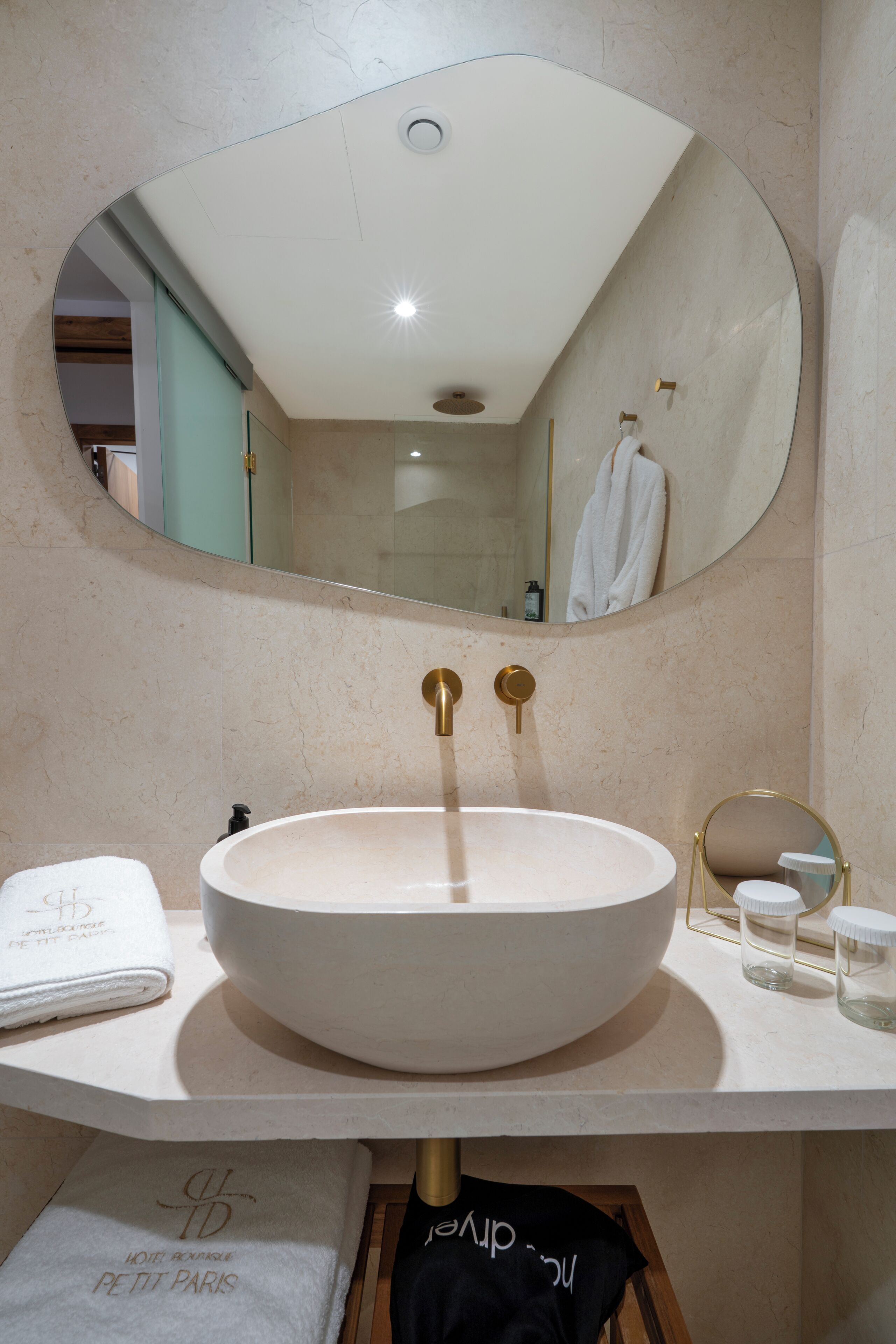 A bathroom with a round sink, a large mirror, and a towel rack.