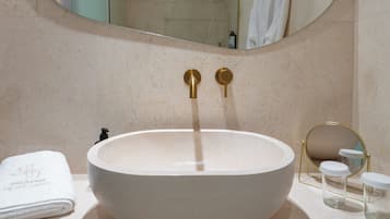 A bathroom with a round sink, a large mirror, and a towel rack.