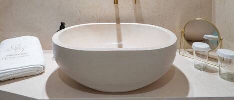 Un baño con un lavabo redondo, un espejo grande y un perchero para toallas.