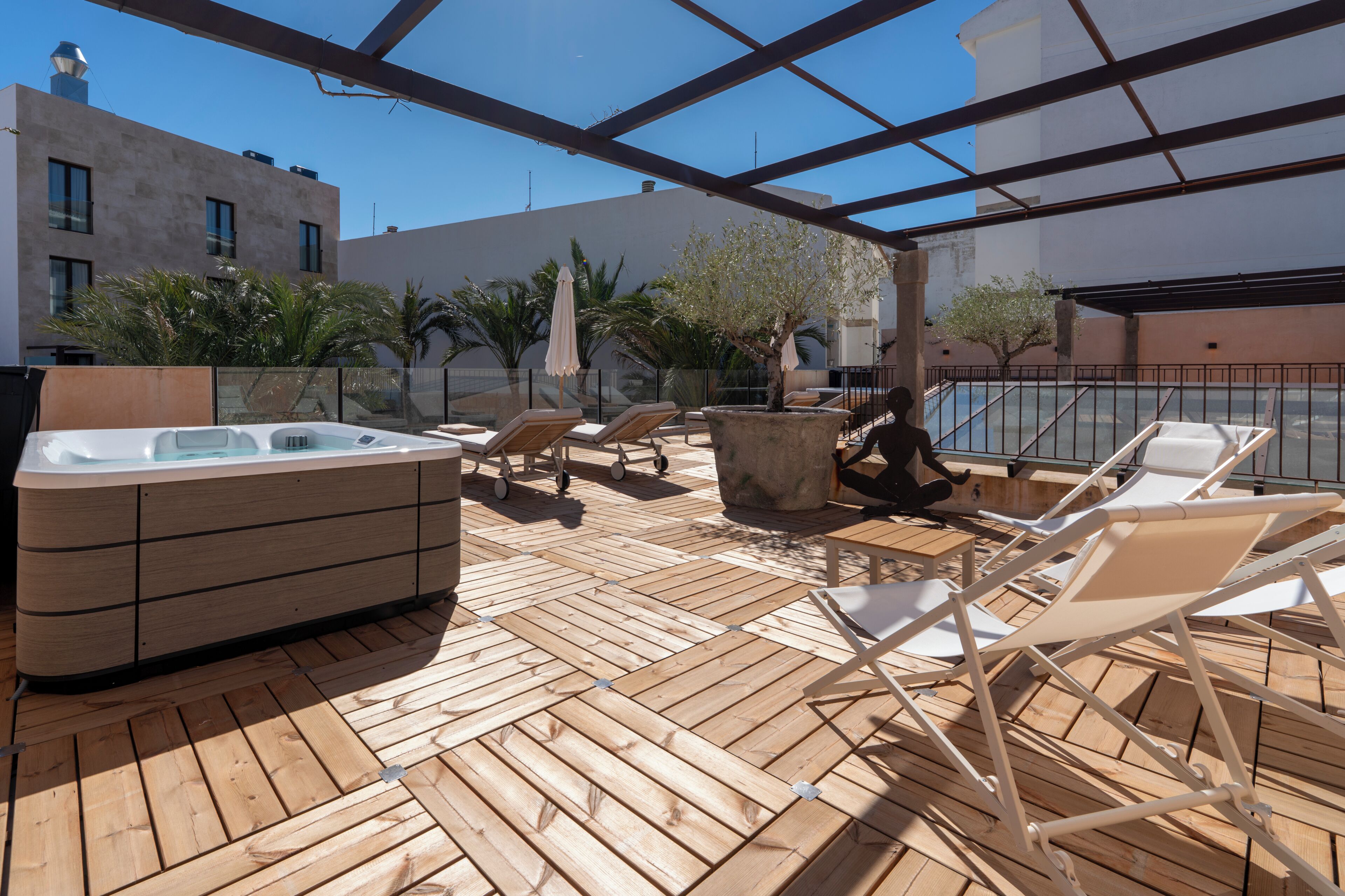 Terraza de madera con sillones, jacuzzi y plantas en macetas.