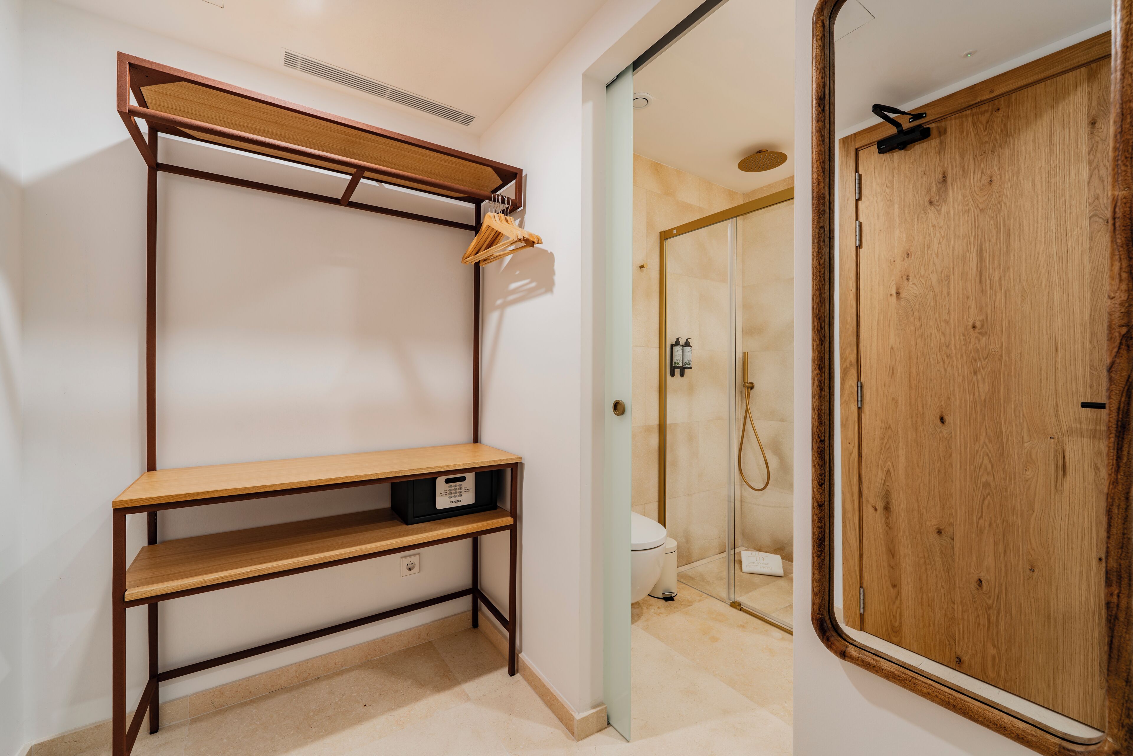 A bathroom with a wooden vanity, a shower, and a door with a mirror.