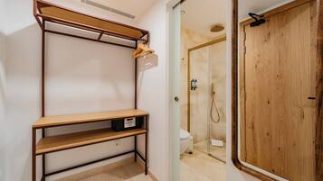 A bathroom with a wooden vanity, a shower, and a door with a mirror.