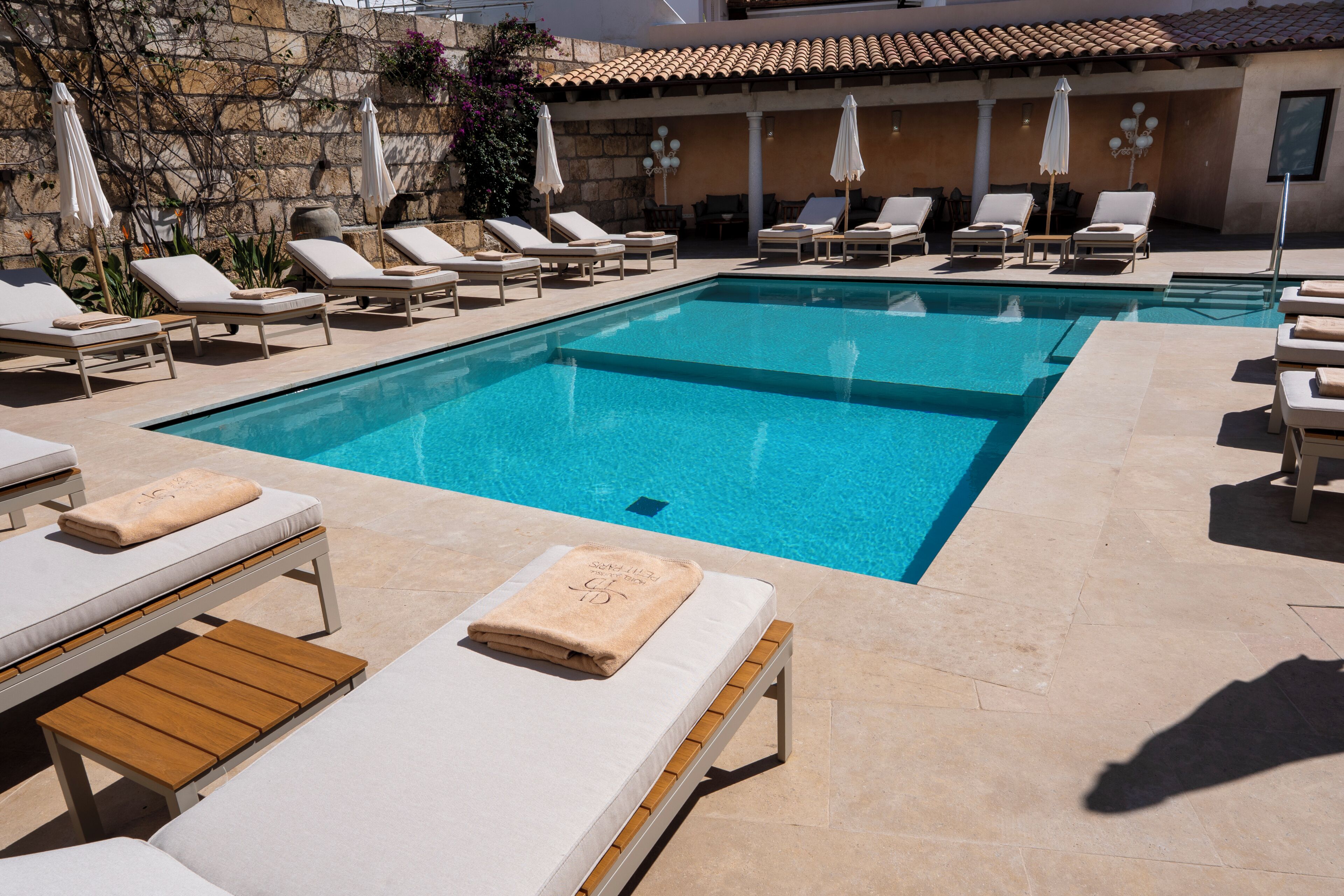 Zona de piscina con tumbonas y una pared de piedra.