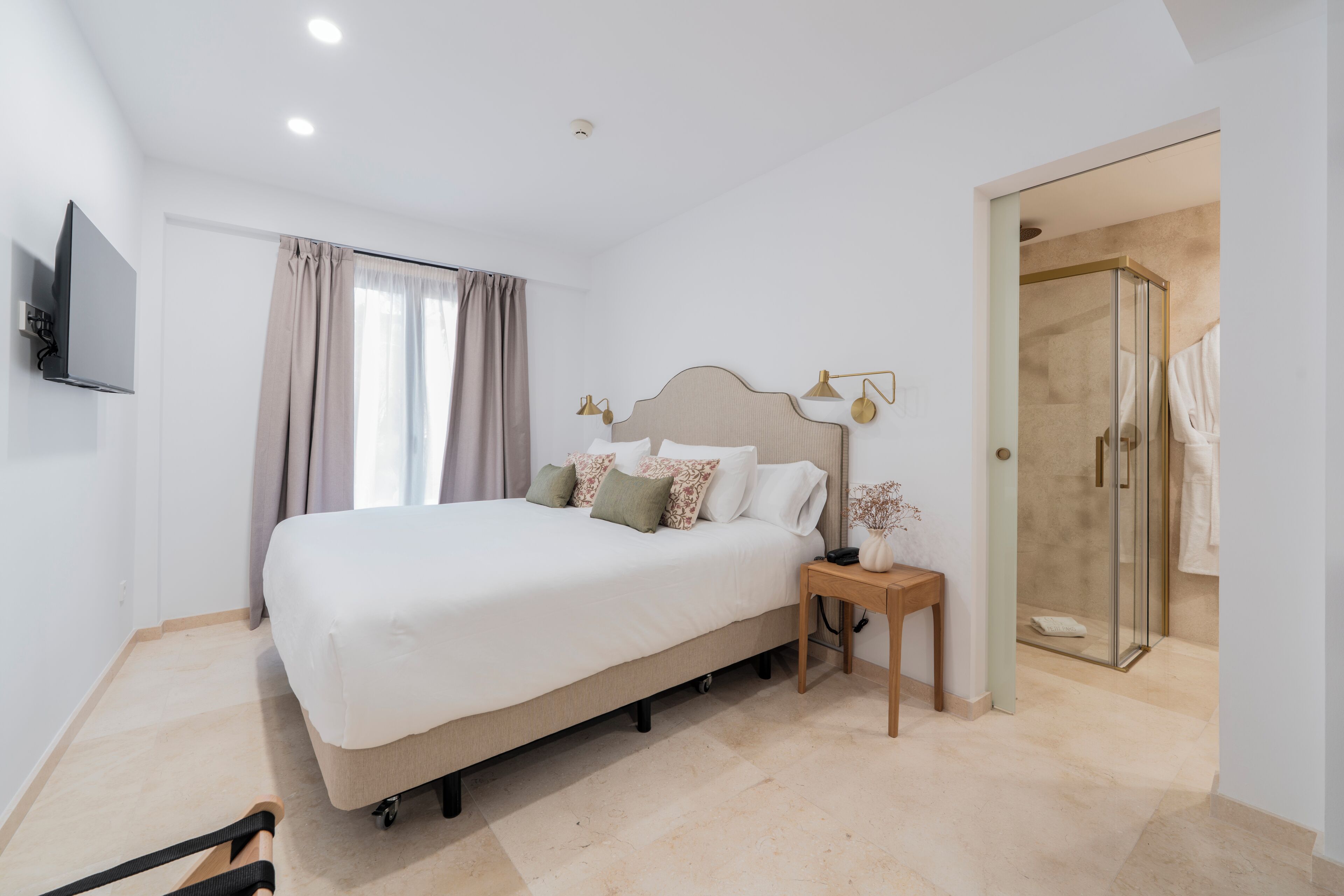 Een slaapkamer met een bed, nachtkastje, lamp en een douchegedeelte.