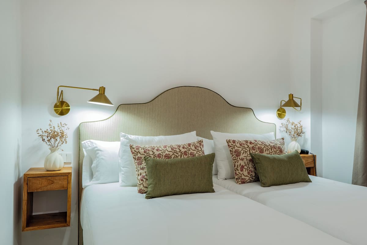 A double bed with white bedding, two nightstands with lamps, and a headboard with a ribbed design.