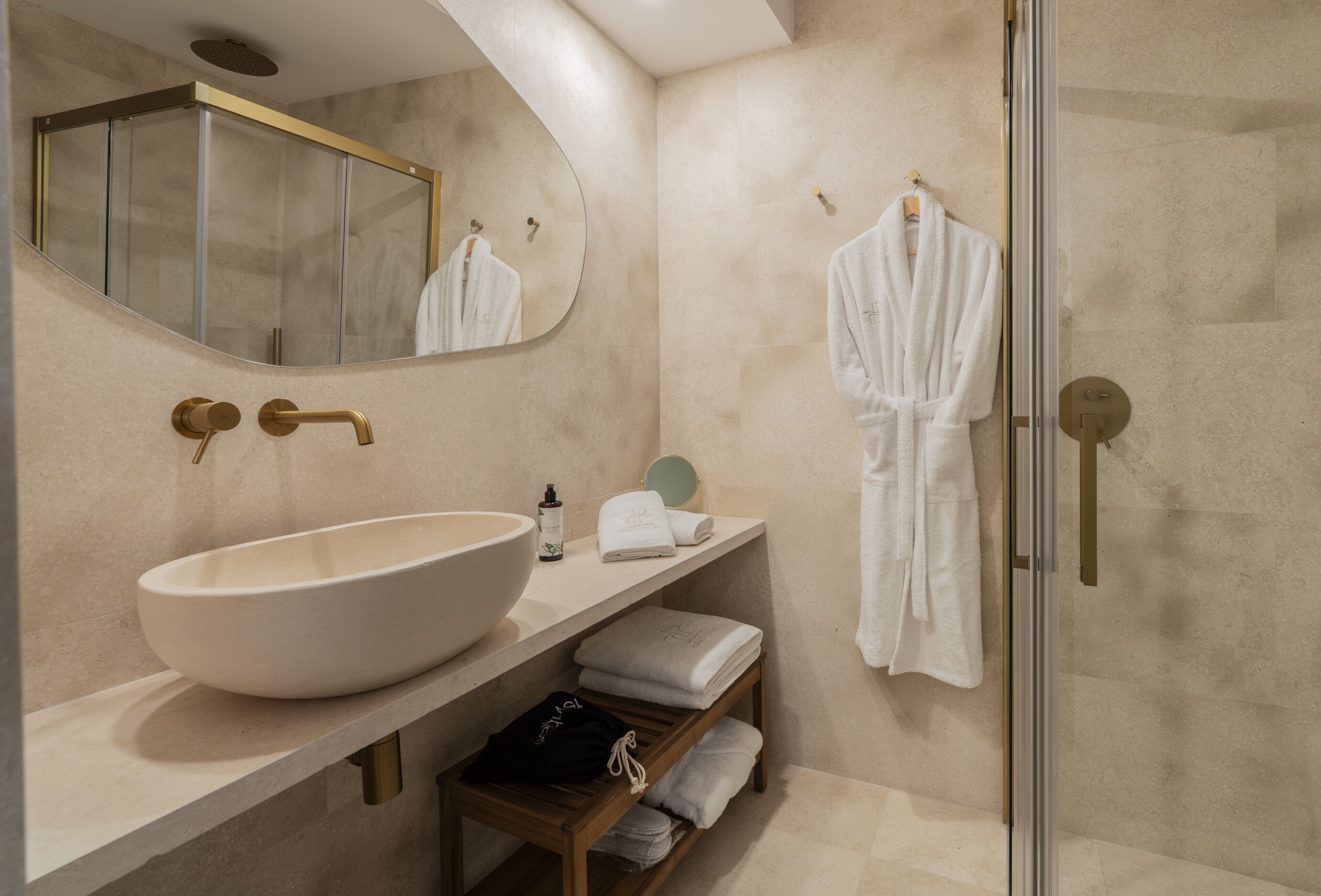 Un baño moderno con un lavamanos ovalado grande, una ducha con cerramiento de vidrio y un espejo.