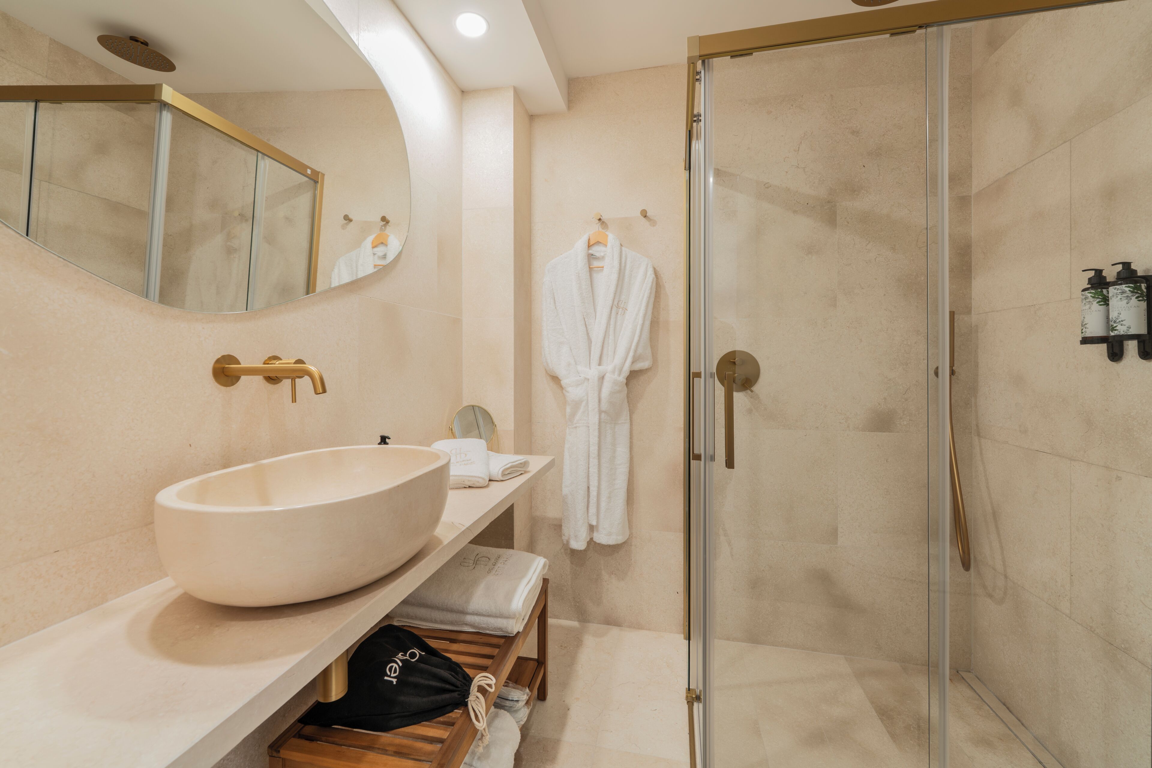 A modern bathroom with a large vessel sink, a glass-enclosed shower, and a robe hanging on a rack.
