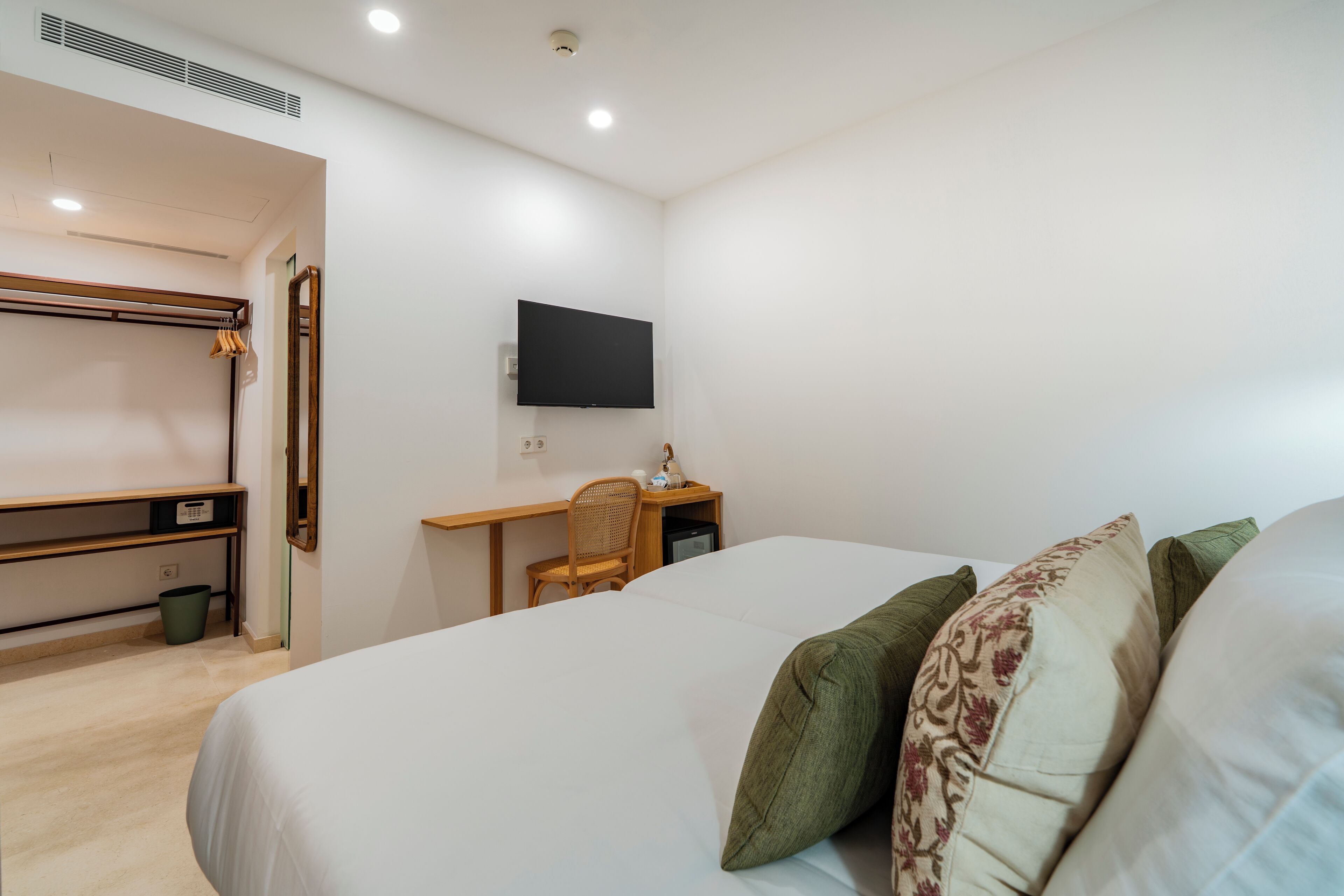 A bedroom with a bed, a desk, a chair, and a television.