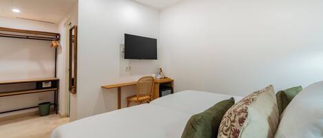 A bedroom with a bed, a desk, a chair, and a television.