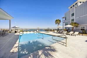 Ein Poolbereich mit freiem Blick auf das Meer, Liegestühle und Sonnenschirme.