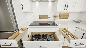 Une cuisine moderne avec des meubles blancs, un réfrigérateur en acier inoxydable et un four encastré.