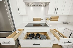 A modern kitchen with white cabinetry, a stainless steel refrigerator, and a built-in oven.