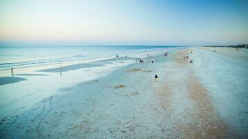 A beach with a wide expanse of sand and a few people scattered across the area.