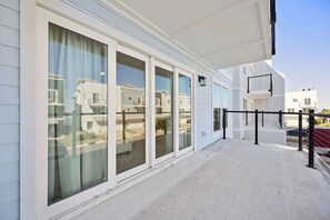 A modern building with large sliding glass doors, a concrete balcony, and a metal railing. - NewConstructionLuxury|Pool|4beds|Downtown (St. Augustine)