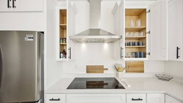 A modern kitchen with white cabinetry, a stainless steel refrigerator, a built-in stove, and wooden shelves.