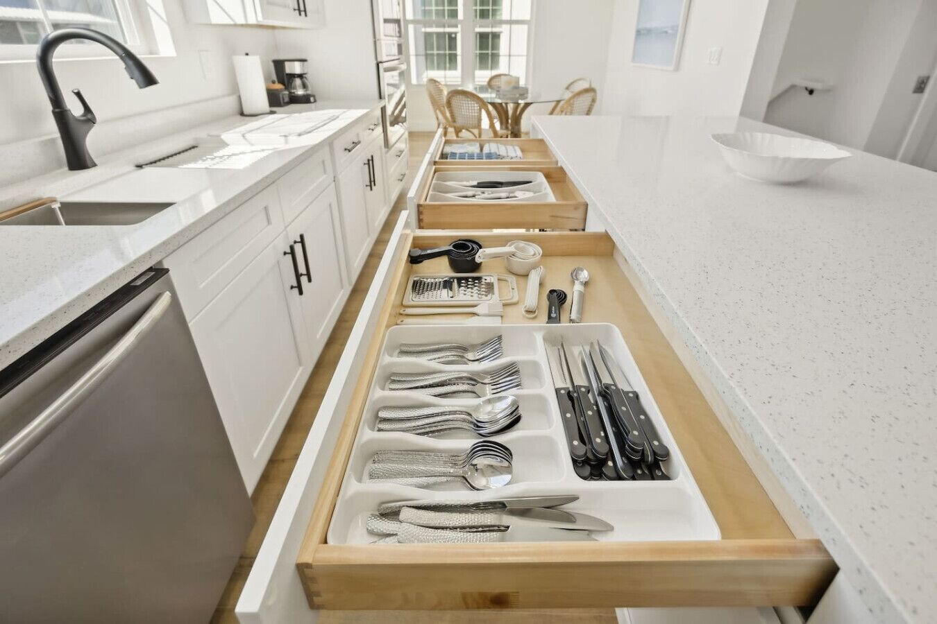 A kitchen with a built-in drawer organizer for utensils, a coffee maker, and a sink.