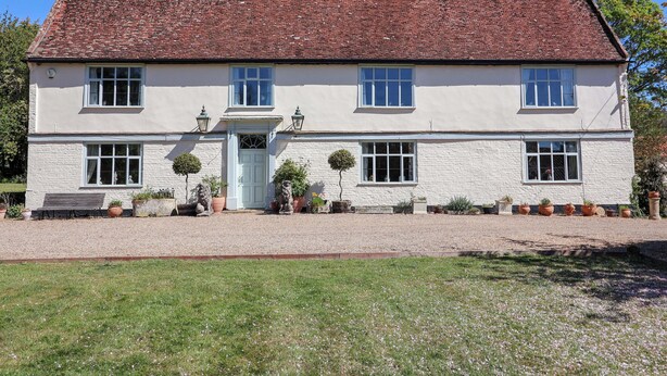 A two-story white building with a red-tiled roof, multiple windows, and a gravel driveway.