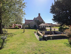 Ett hus med en trädgård, en lusthus och en fontän.