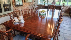 A large wooden dining table with chairs, a tray with teapots and cups, and a decorative centerpiece.