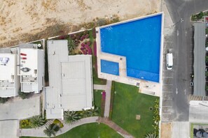 An aerial view of a property with a large swimming pool, a covered outdoor area, and a parking lot. - Above The Arch: Penthouse w/ Private Rooftop Pool (Cabo San Lucas)