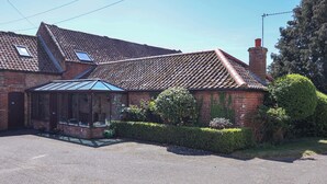 A brick building with a tiled roof, a conservatory, and a chimney. - Winston Lodge (Beccles)