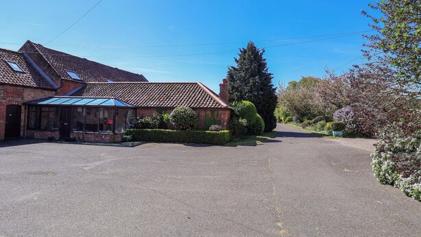 A building with a tiled roof, a covered porch, and a gravel driveway. - Winston Lodge (Beccles)