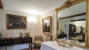 A room with a dining table set for a meal, a large ornate mirror, and a chair. - Winston Lodge (Beccles)